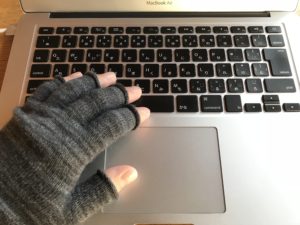 手袋をはめてパソコンを打つ手