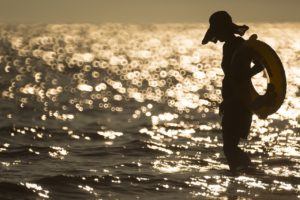 夕日をバックに海岸を歩く女性